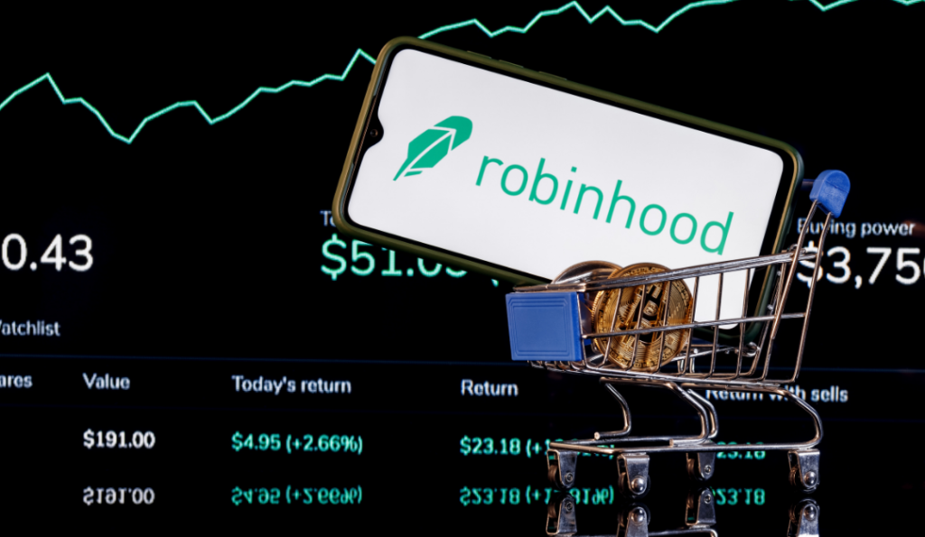 Small trolley with bitcoins in and a cell phone with the word "robinhood" written on it.