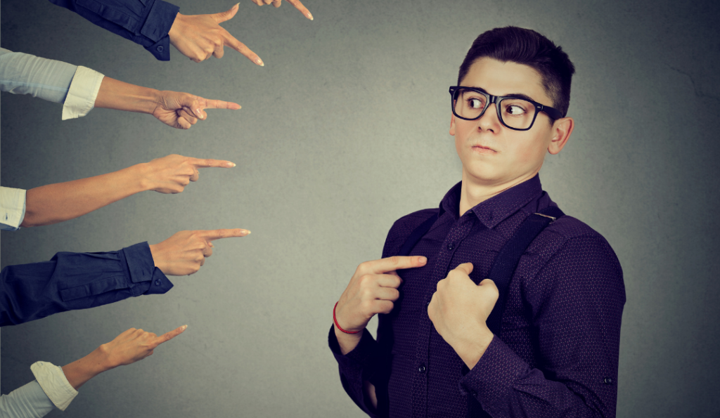 Fingers pointing at a guy wearing glasses.