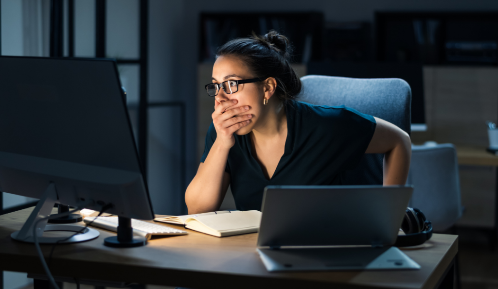 Woman sitting in front of computer looking shocked.