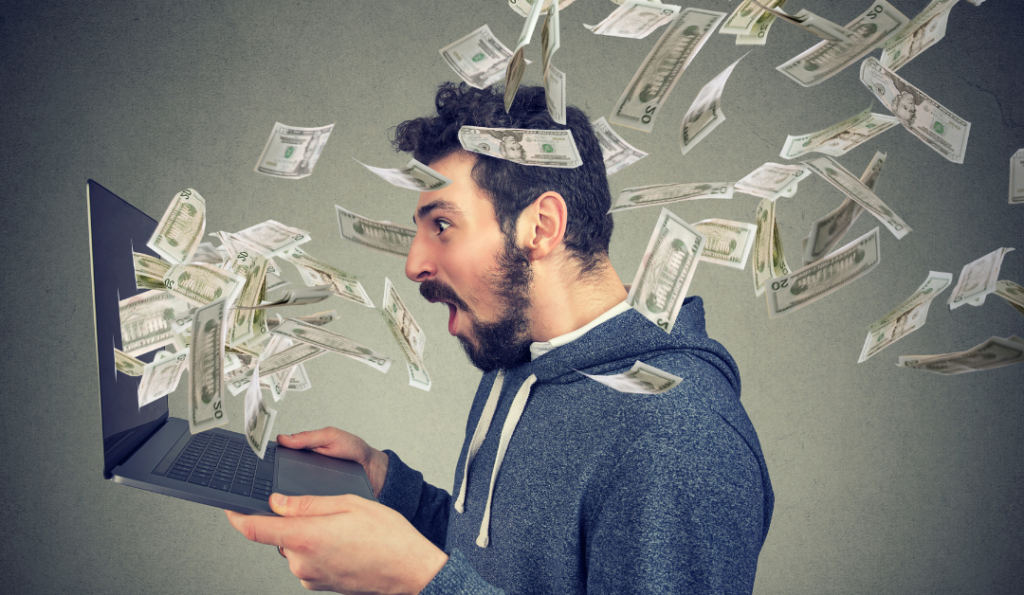 Guy looking excited with computer in his hands and money falling on him.
